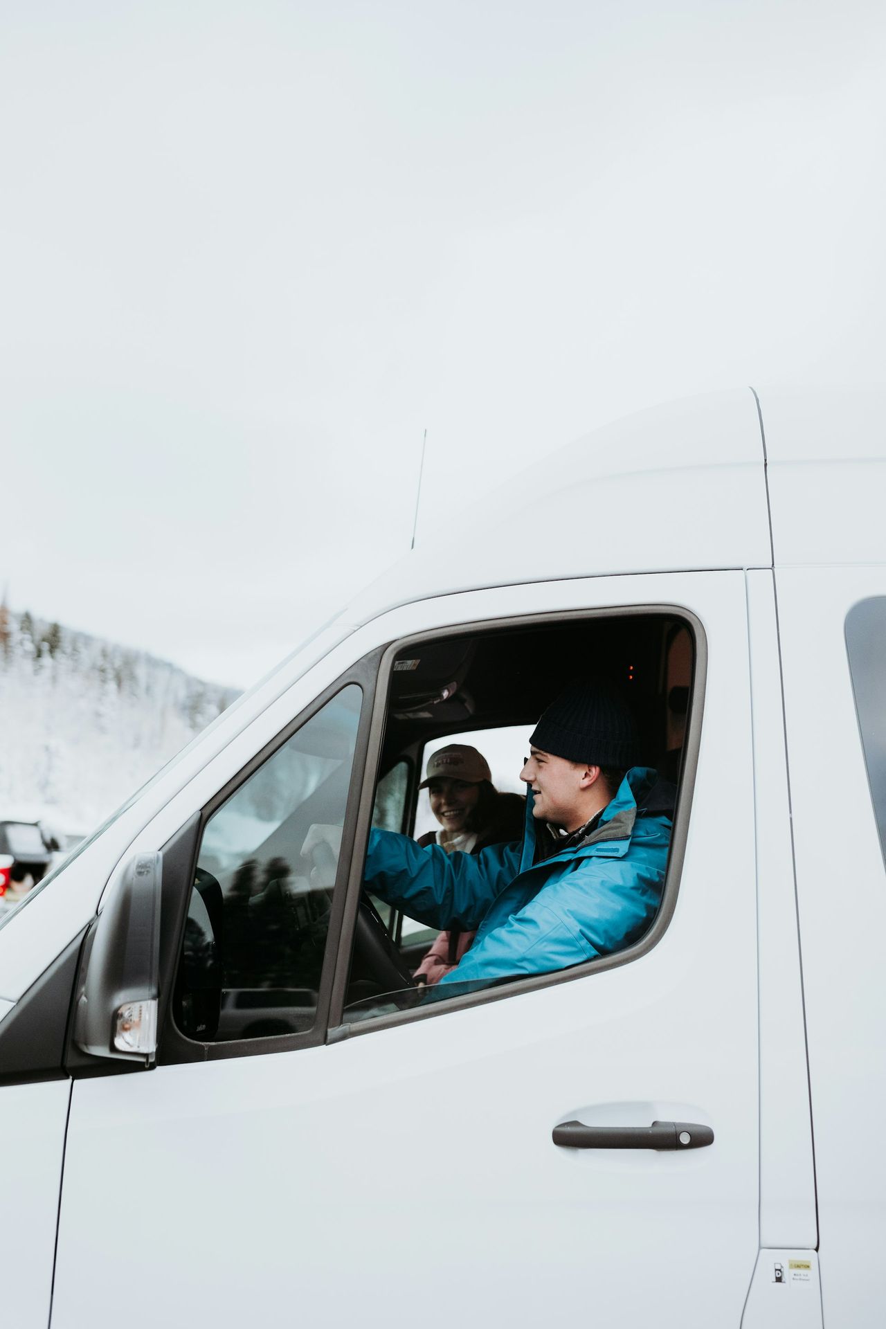 a man driving a white van down a snow covered road